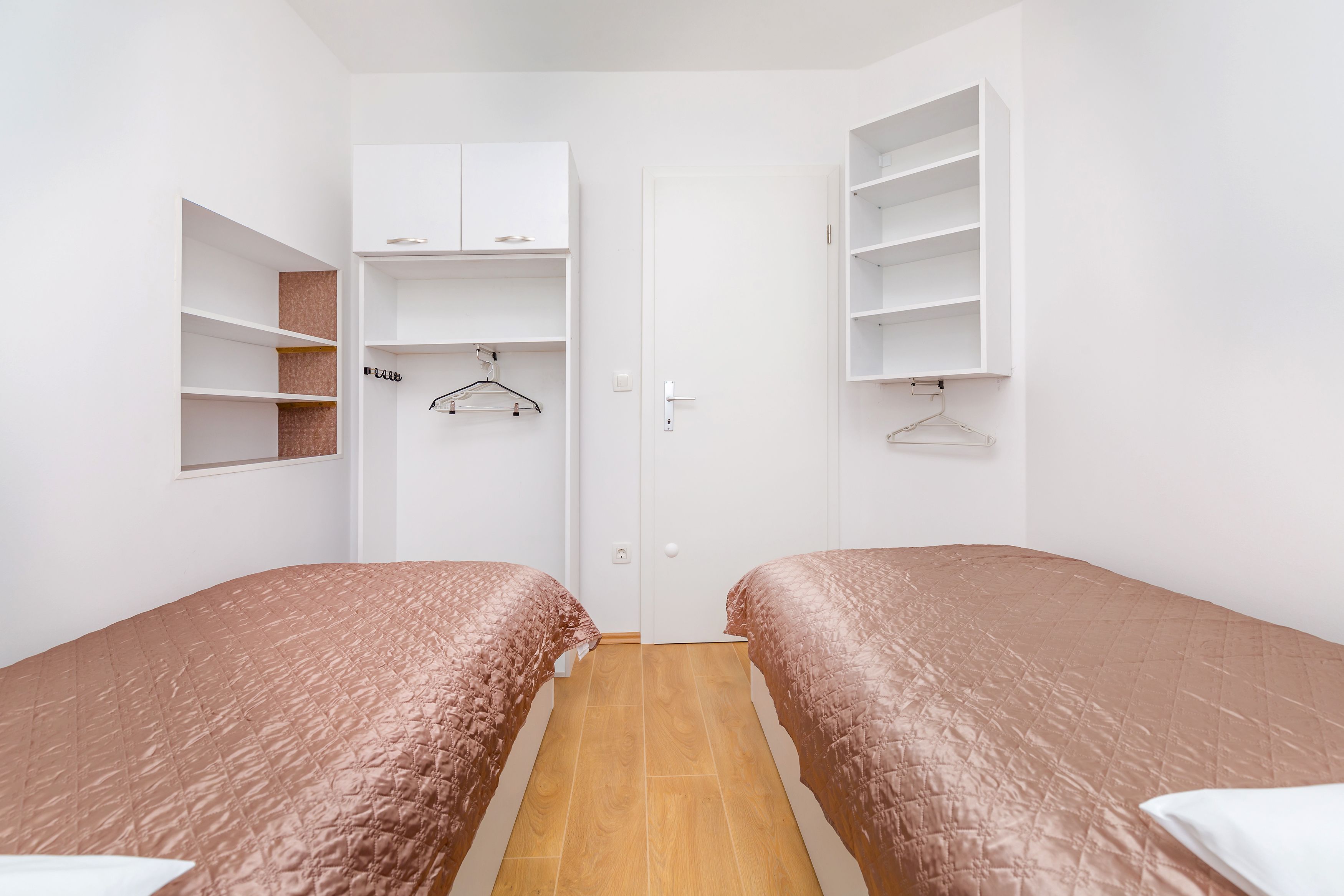 Une chambre avec deux lits, une armoire et un placard.