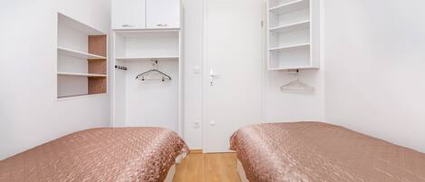 A bedroom with two beds, a wardrobe, and a closet.