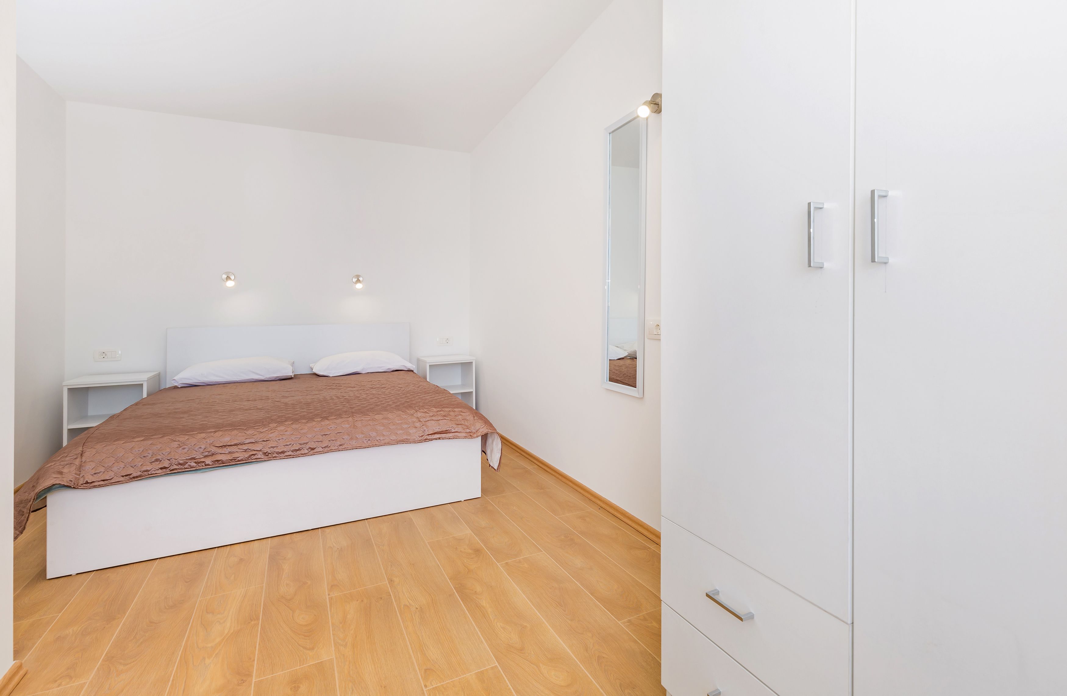 Un dormitorio con cama, mesitas de noche, armario y espejo.
