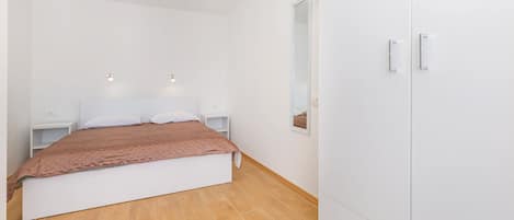 Un dormitorio con cama, mesitas de noche, armario y espejo.