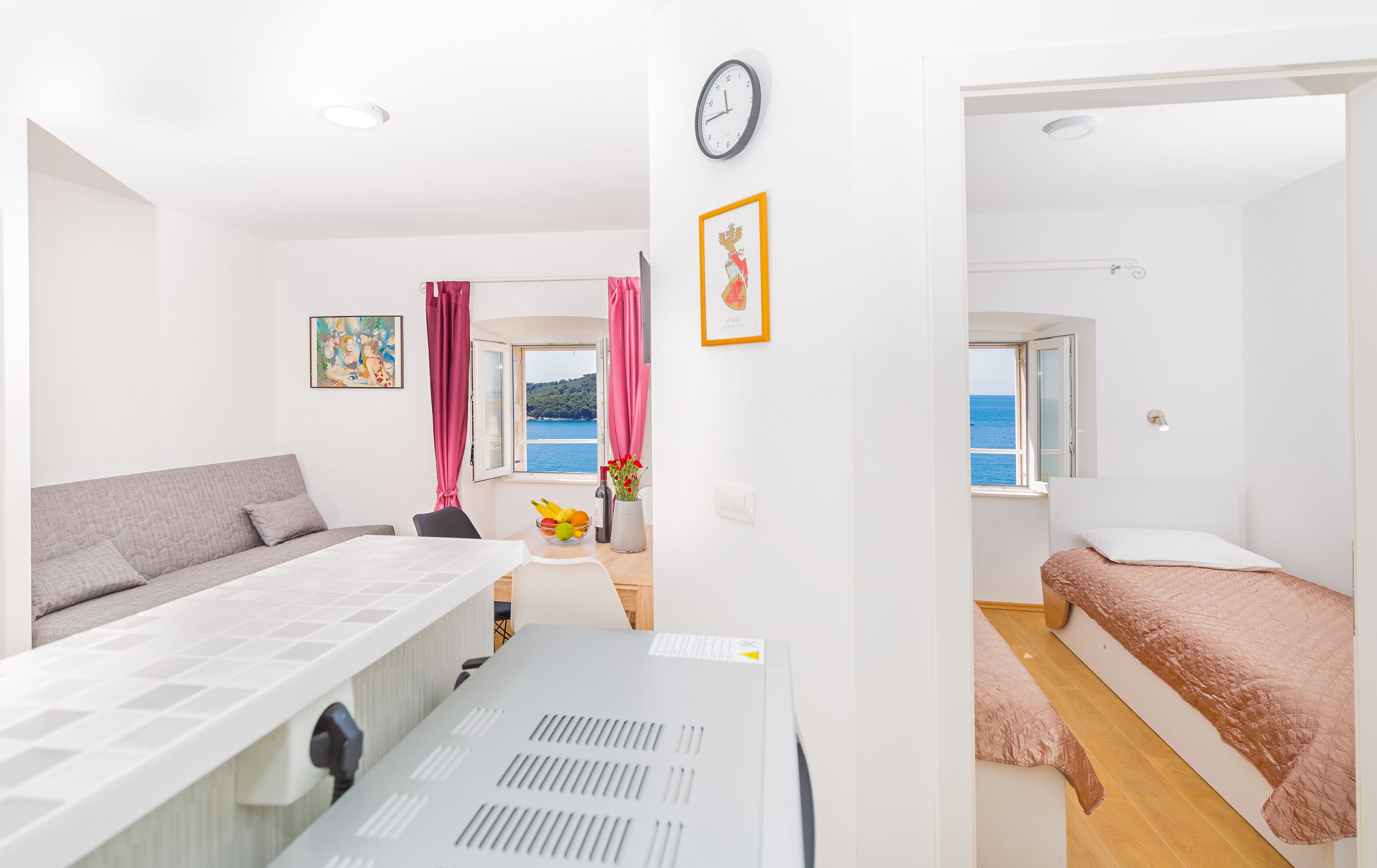 Ein modernes, helles Zimmer mit einem Bett, einem Schreibtisch und Meerblick.