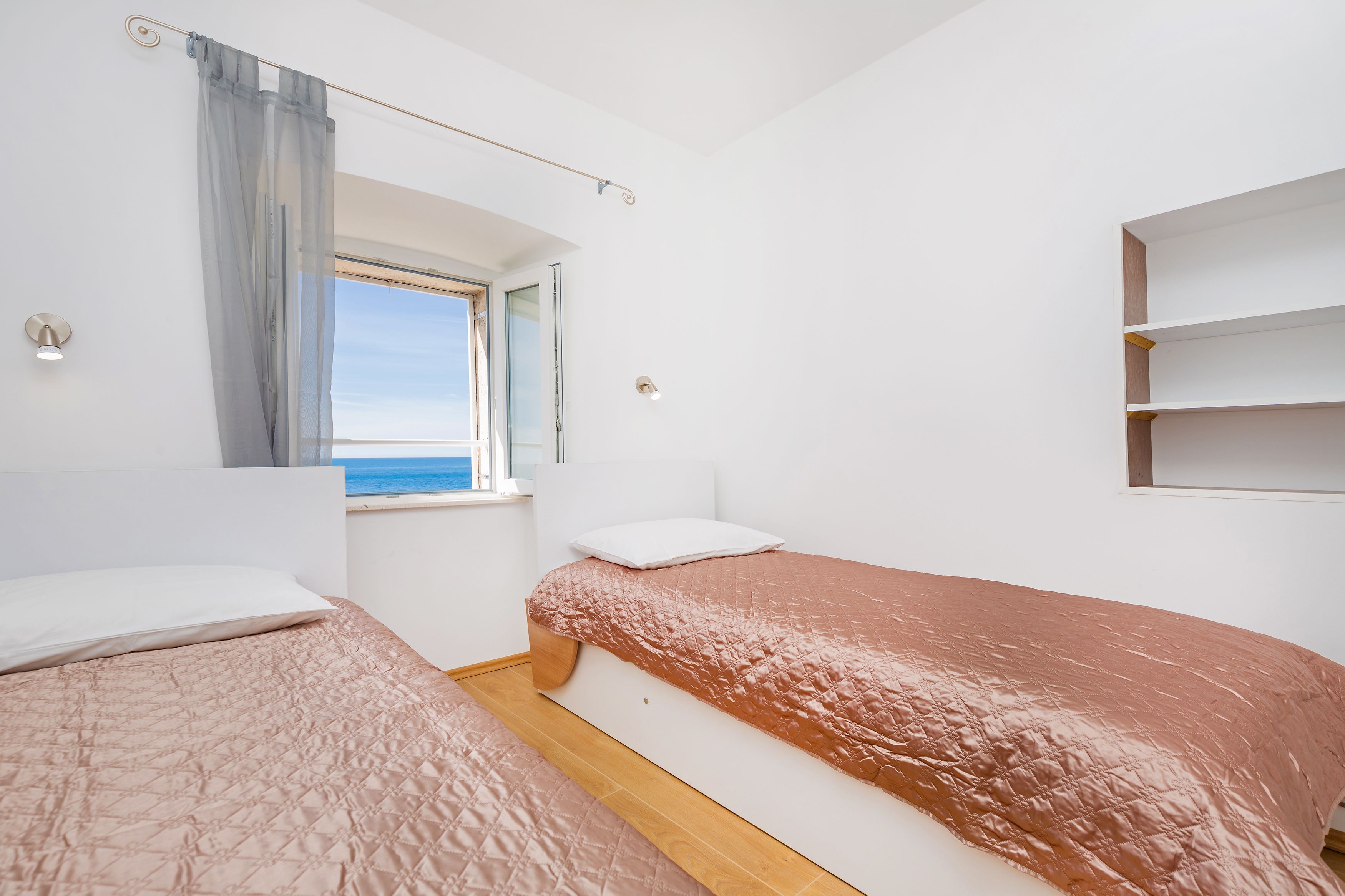 Un dormitorio con dos camas, una ventana con vistas y un estante empotrado.