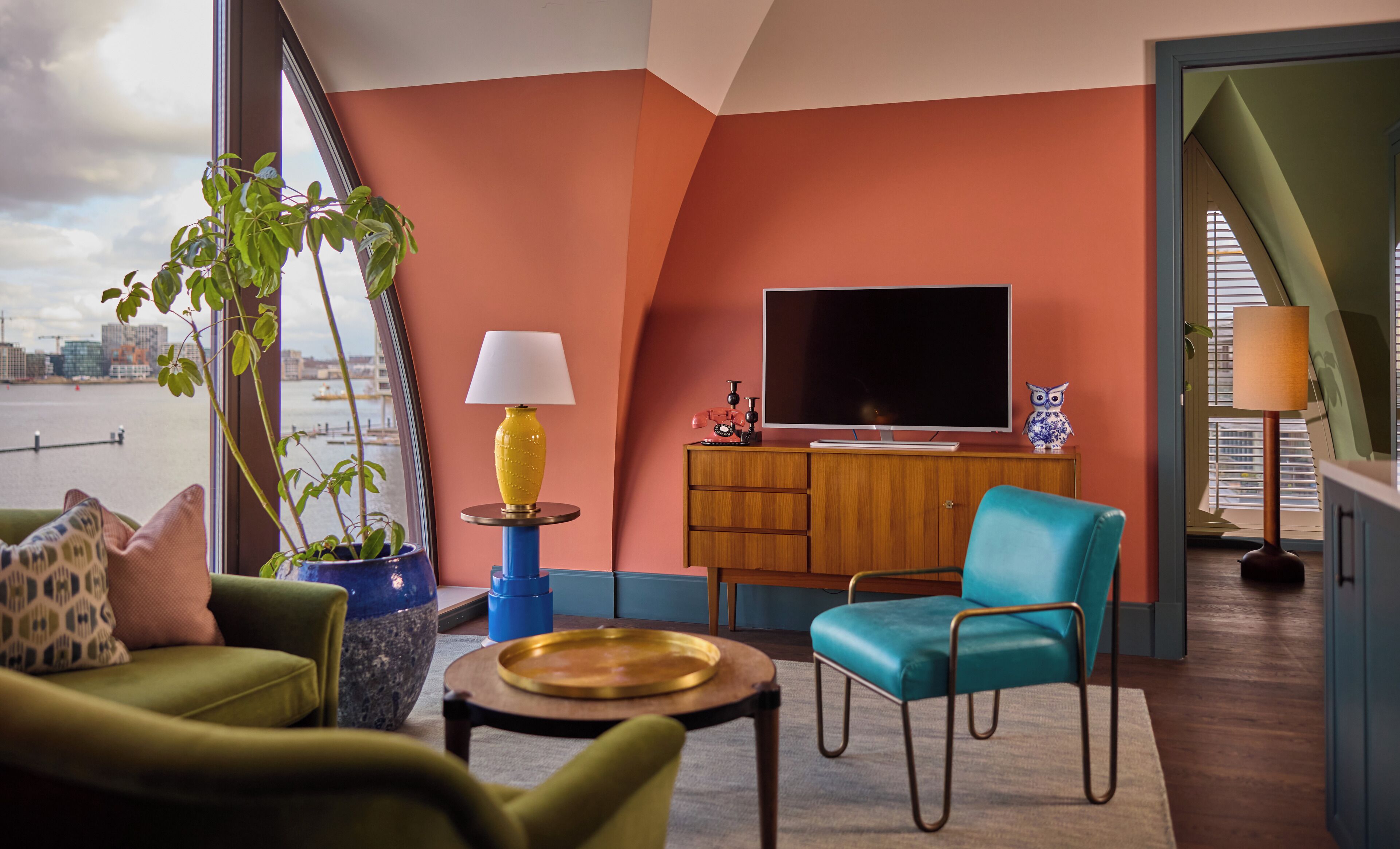A modern living room with a city view, a television, and a blue chair.