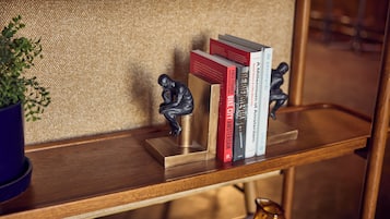 A wooden shelf with books, a small sculpture, and a potted plant.