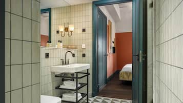 A bathroom with a white sink, a mirror, and a shelf with towels.
