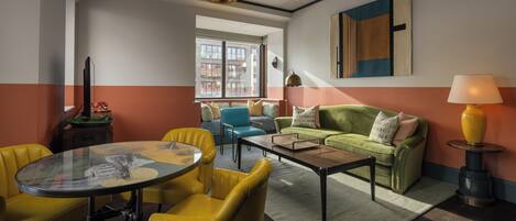 Un salon moderne avec une table basse en verre, des fauteuils jaunes, un canapé vert et une lampe.