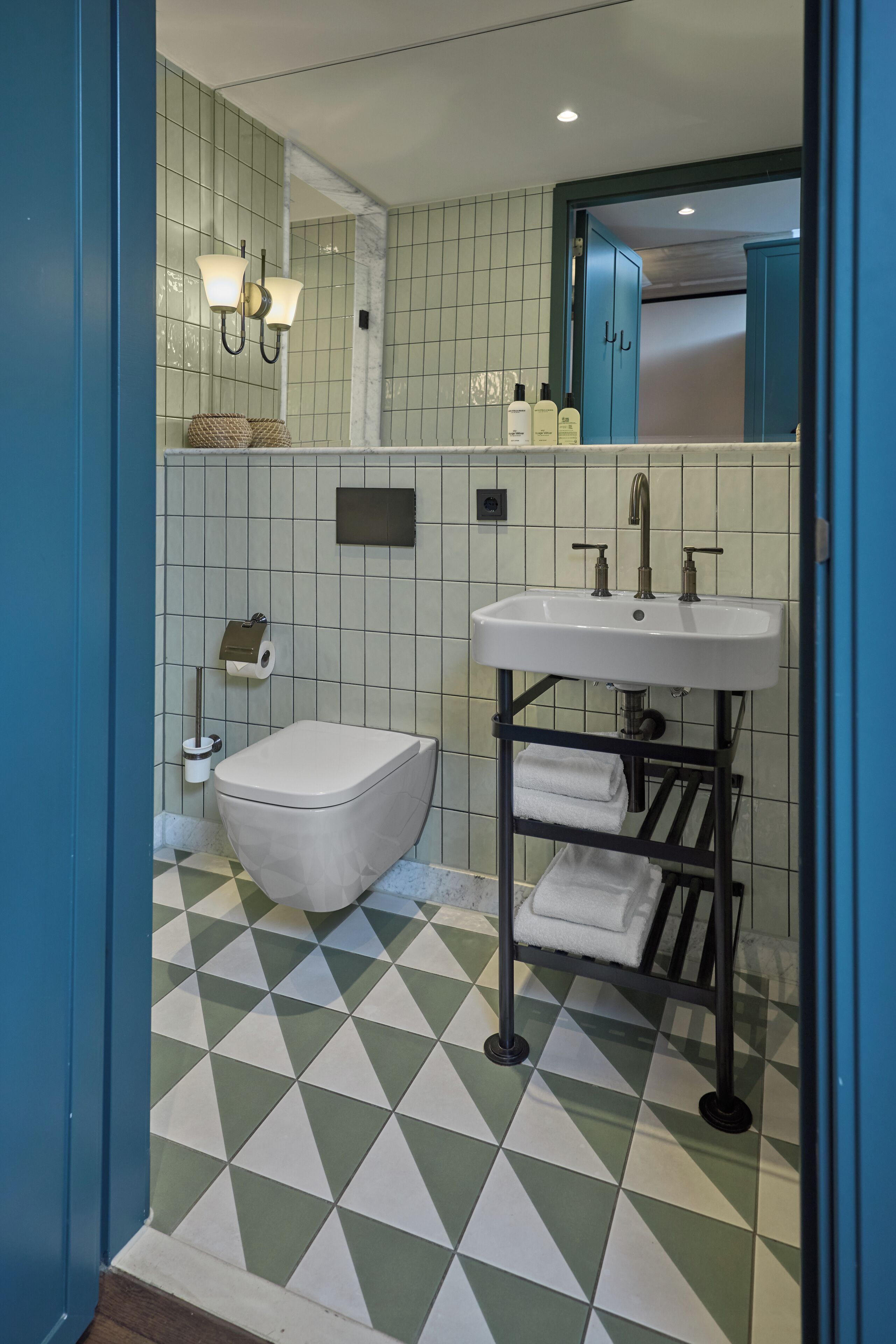A bathroom with a white toilet, a white sink with a towel rack, and a mirror above the sink.