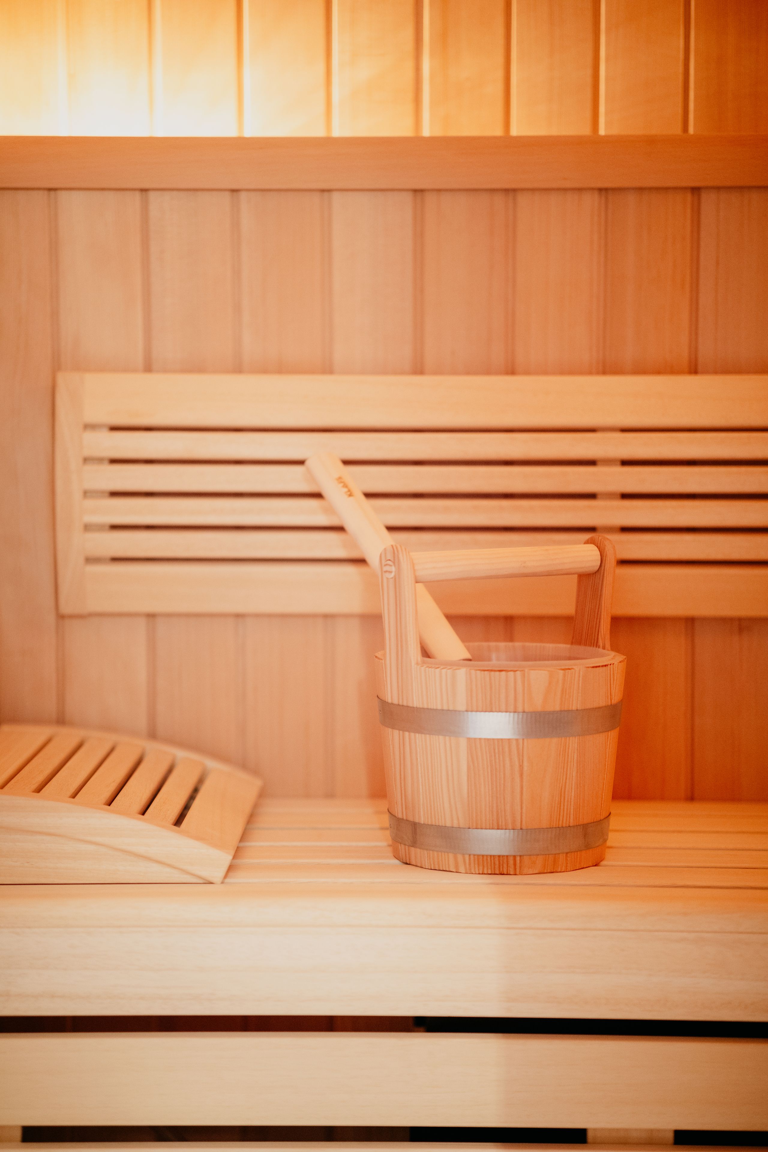 A wooden sauna bench with a wooden bucket and a wooden ladle.