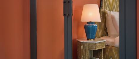 A blue lamp on a small wooden table with a stack of books underneath.