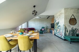 A dining area with a wooden table set for four, yellow chairs, and a green sofa in the background.