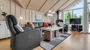 Un salon chaleureux avec un plafond en bois, un canapé, une table basse et un téléviseur.