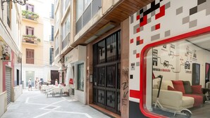 Eine enge Stadtstraße mit einem Café, einem geschlossenen Geschäft und einem Wohngebäude mit roter und weißer Fassade.