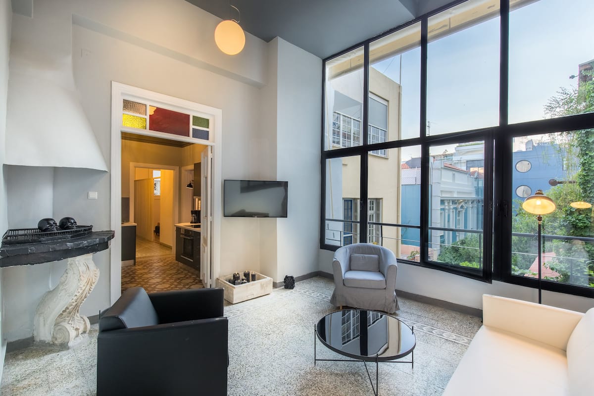 Ein modernes Wohnzimmer mit großem Fenster, Flachbildfernseher und einer Couch.