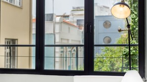 Una habitación con un ventanal grande, un sofá blanco y una lámpara de pie.