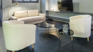 Una sala de estar moderna con un sofá, dos sillones, una mesa de centro, un televisor y un ventanal grande.