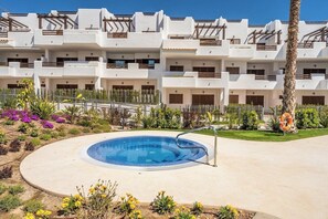 A modern hotel with a swimming pool surrounded by a landscaped garden.