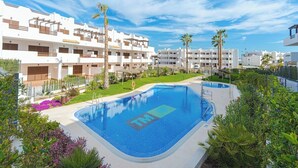 A swimming pool with a logo, surrounded by greenery and white buildings.