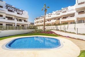 A modern residential building with a swimming pool, balconies, and a well-maintained garden.