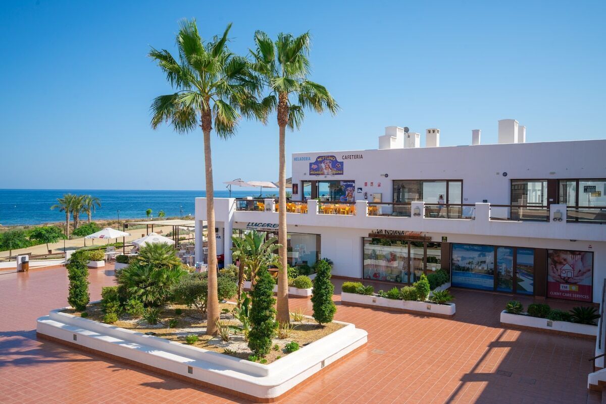 A hotel with a beach view, palm trees, and outdoor seating areas.