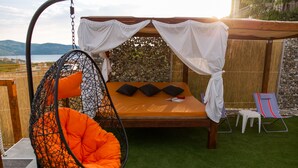 A bed with a canopy, a hanging chair, and a small table with a chair. - Villa Hedonist (Seget)