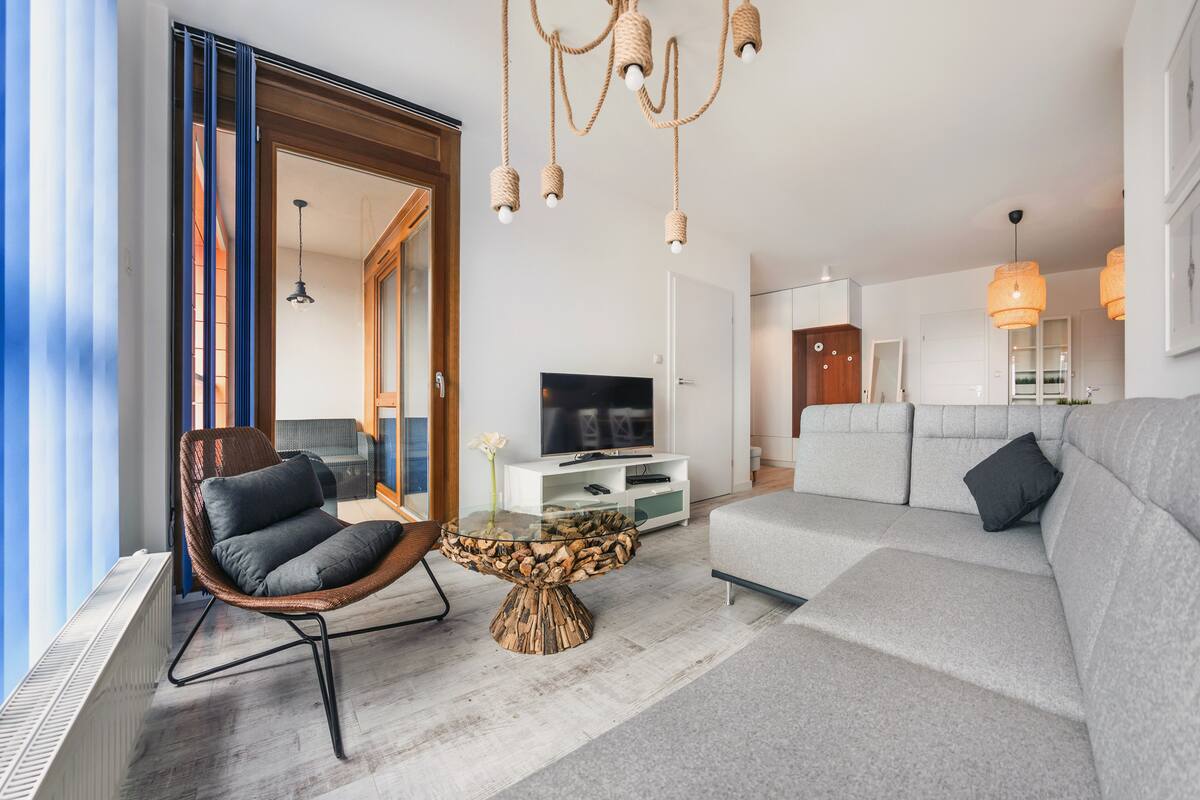 Een moderne woonkamer met een bank, een glazen salontafel, een stoel, een televisie en een kroonluchter.