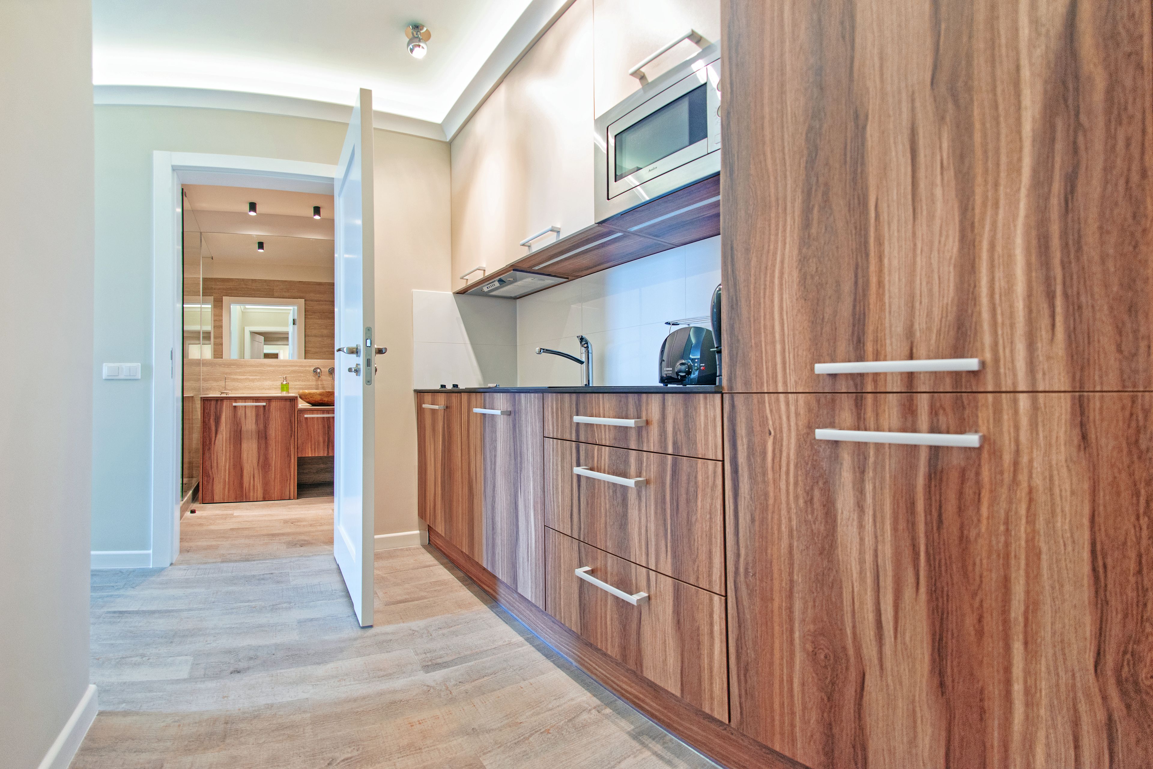 Une cuisine moderne avec des meubles en bois, un four à micro-ondes et un évier en acier inoxydable.