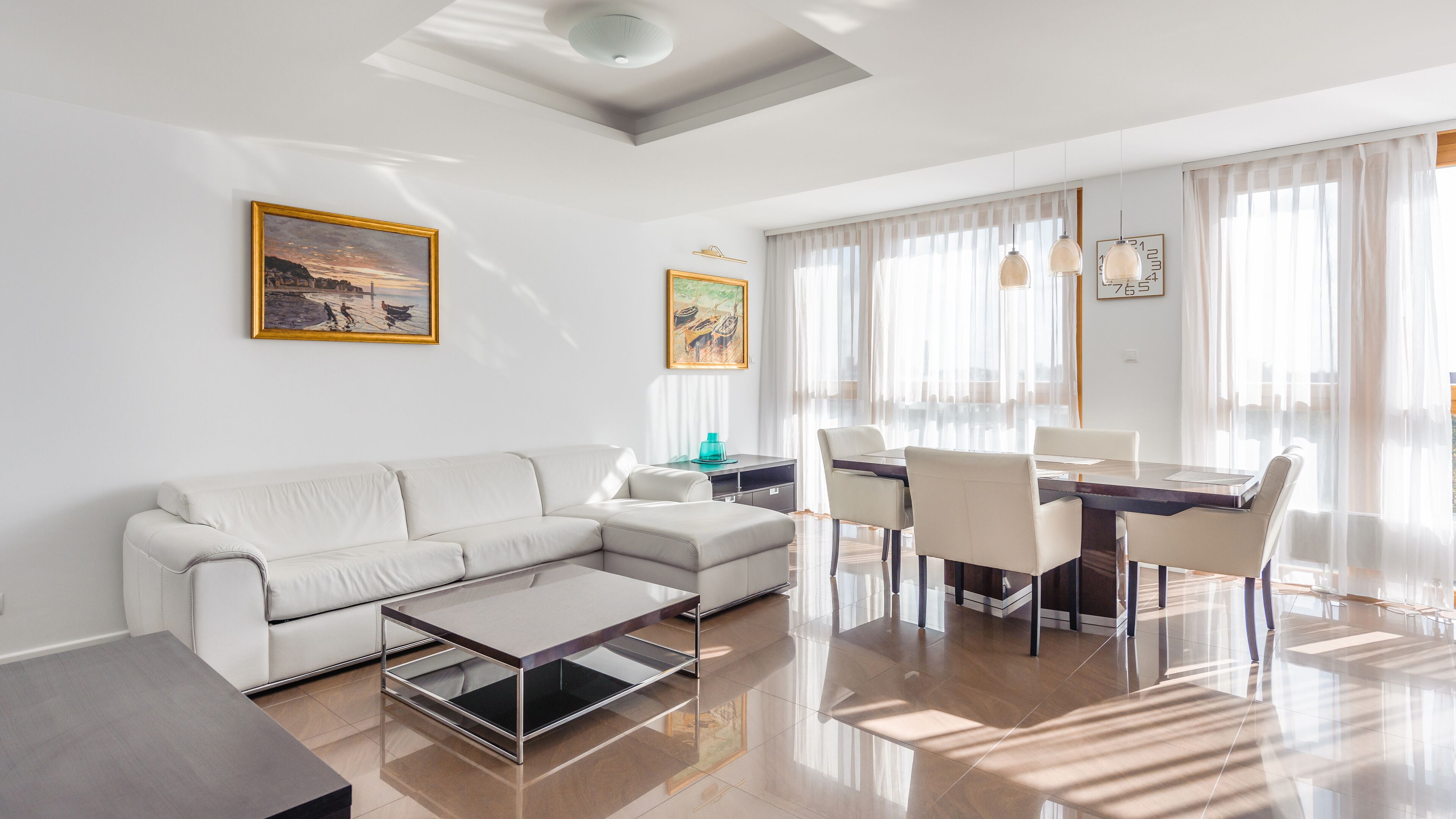 A modern living room with a sofa, coffee table, and dining area with chairs and a table.