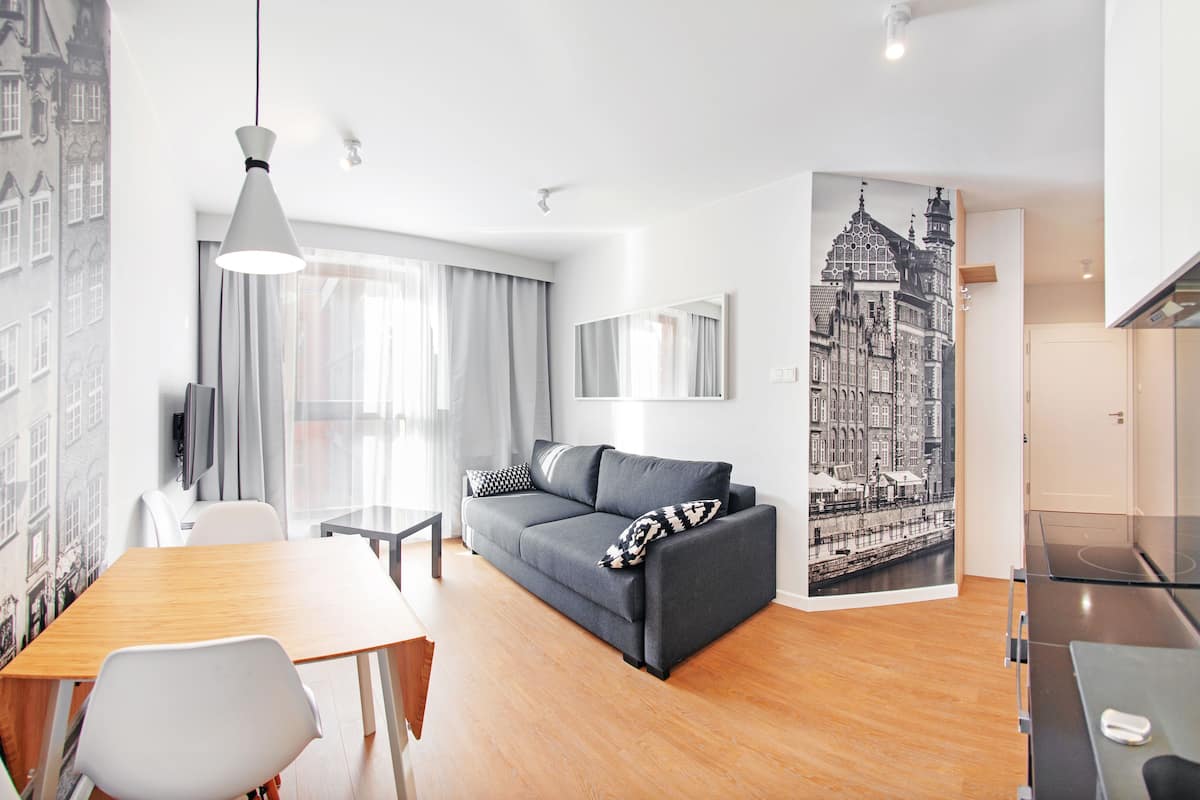 Een moderne woonkamer met een bank, een eettafel en een tv aan de muur.