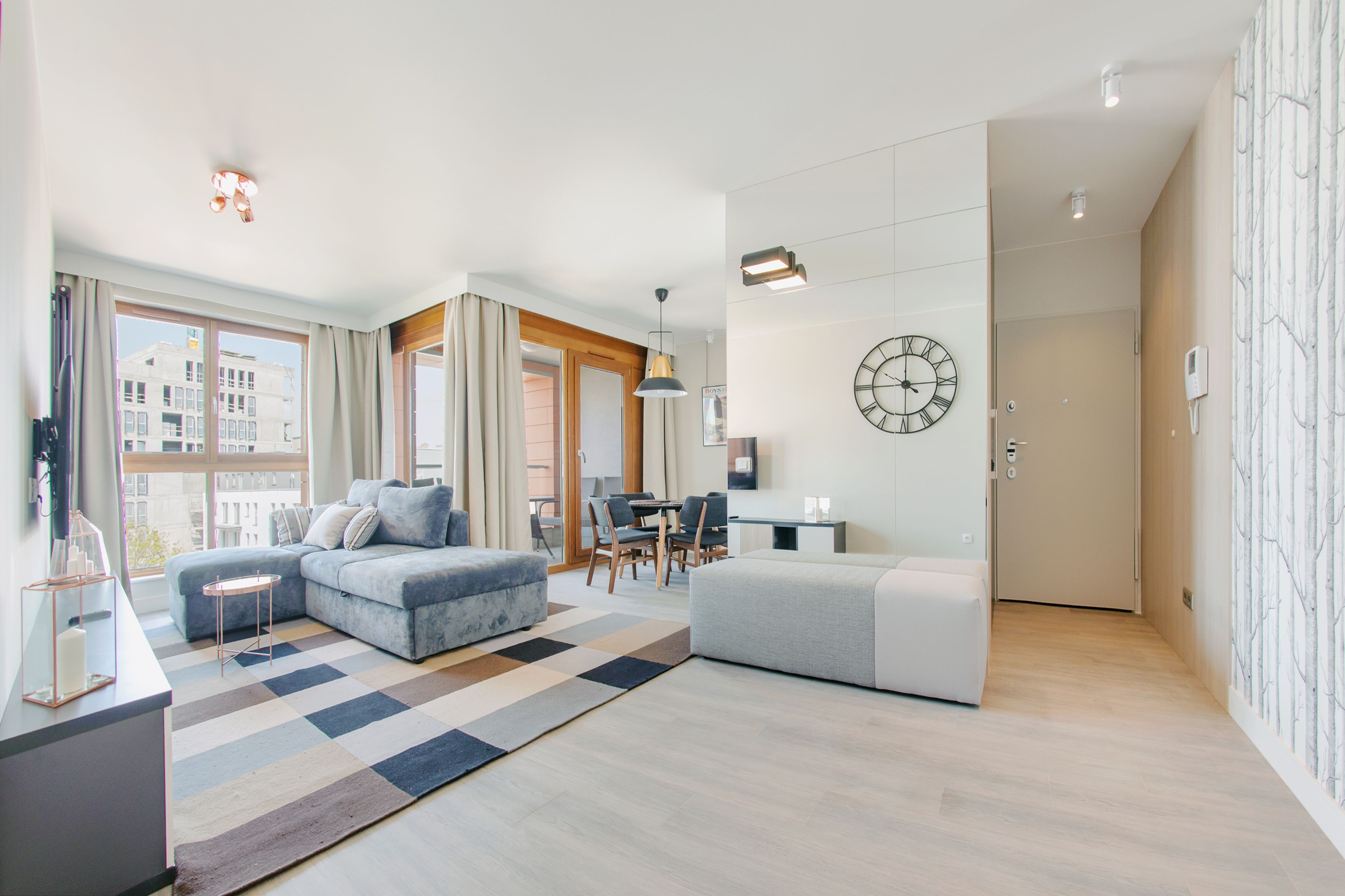 Una sala de estar moderna con un sofá, un reposapiés y un comedor.