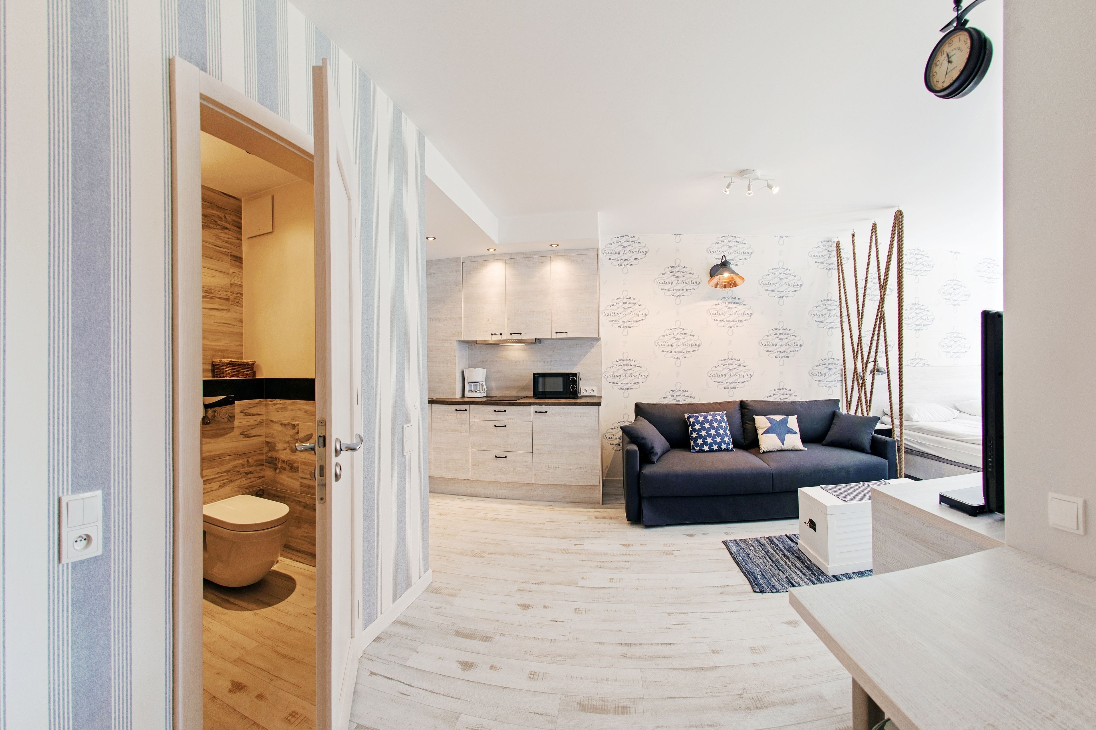 Un apartamento moderno con cocina, sala de estar con sofá y piso de madera.