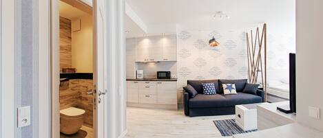 A modern apartment with a kitchen, a living area with a sofa, and a wooden floor.