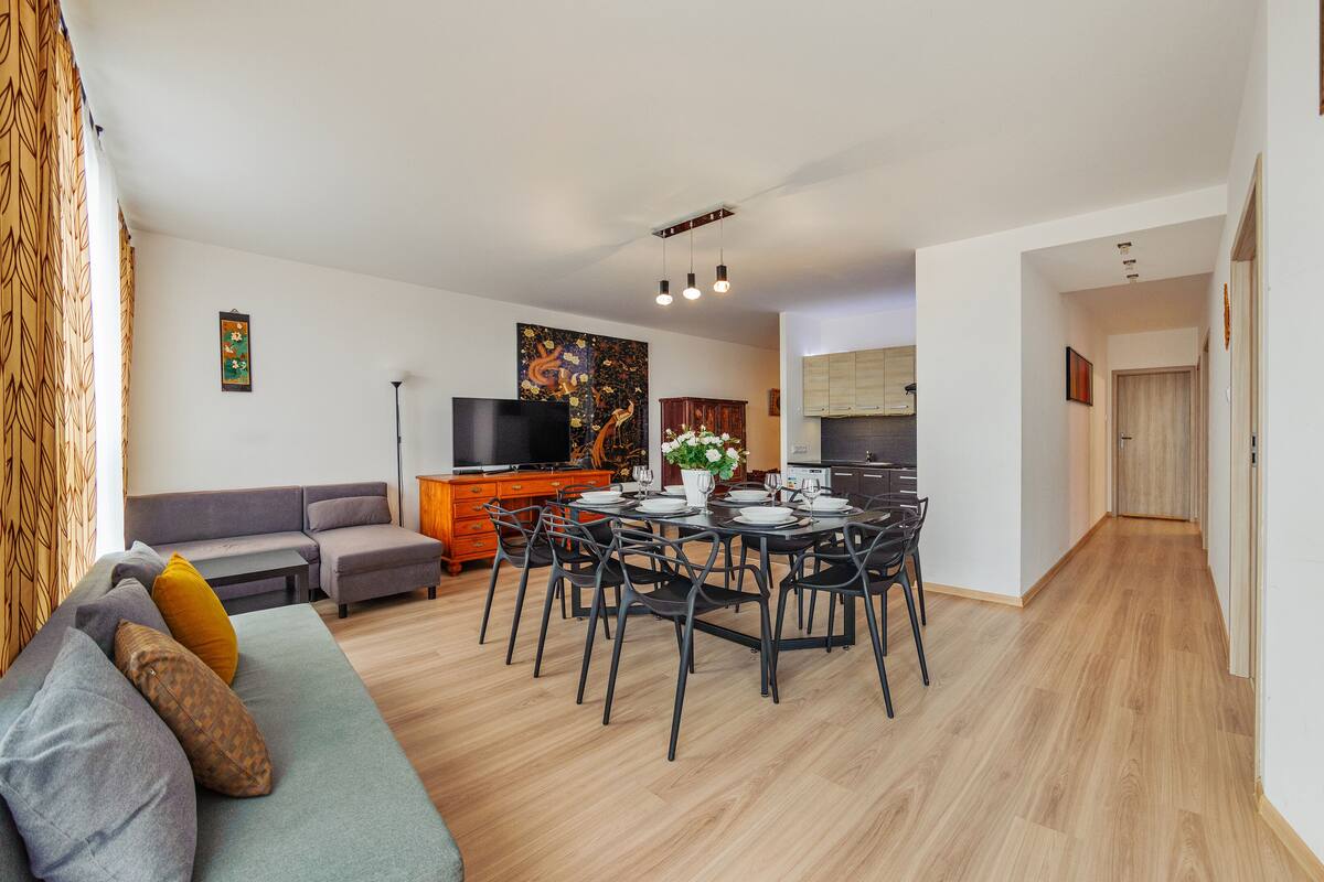 Een moderne woonkamer met een bank, eettafel en televisie.