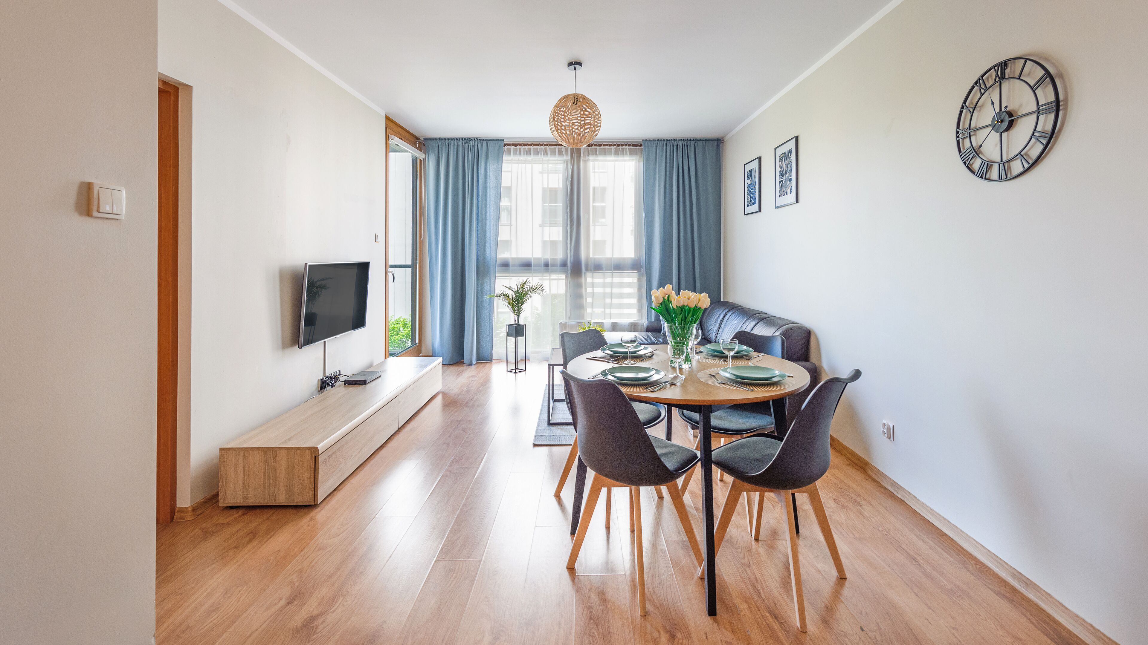 Un comedor moderno con una mesa redonda, sillas y un televisor sobre un mueble.