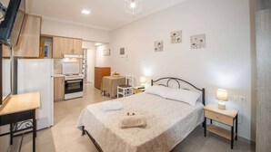 Een slaapkamer met een bed, nachtkastjes, een bureau en een kitchenette.