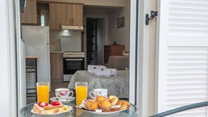 Een ontbijttafel met toast, gebak en sinaasappelsap in een kamer met een bed, een kaptafel en een keukenhoek.