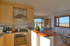 A kitchen with wooden cabinets, a stove, and a dining area with a table and chairs.