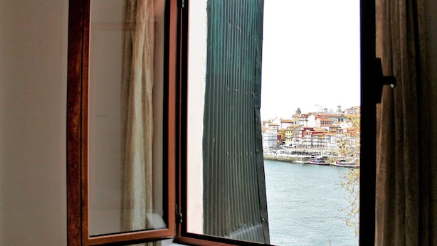 A window with a view of a river and buildings across it. - T2 suites vista rio Douro (Vila Nova de Gaia)