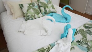 A neatly made bed with white linens, a blue towel, and a white towel. - T2 suites vista rio Douro (Vila Nova de Gaia)