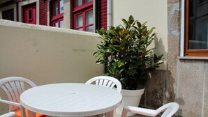 A white round table with four white chairs, each with an orange cushion. There is a potted plant to the right of the table. - T2 suites vista rio Douro (Vila Nova de Gaia)