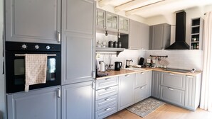 A modern kitchen with grey cabinets, a black oven, and a wooden countertop.