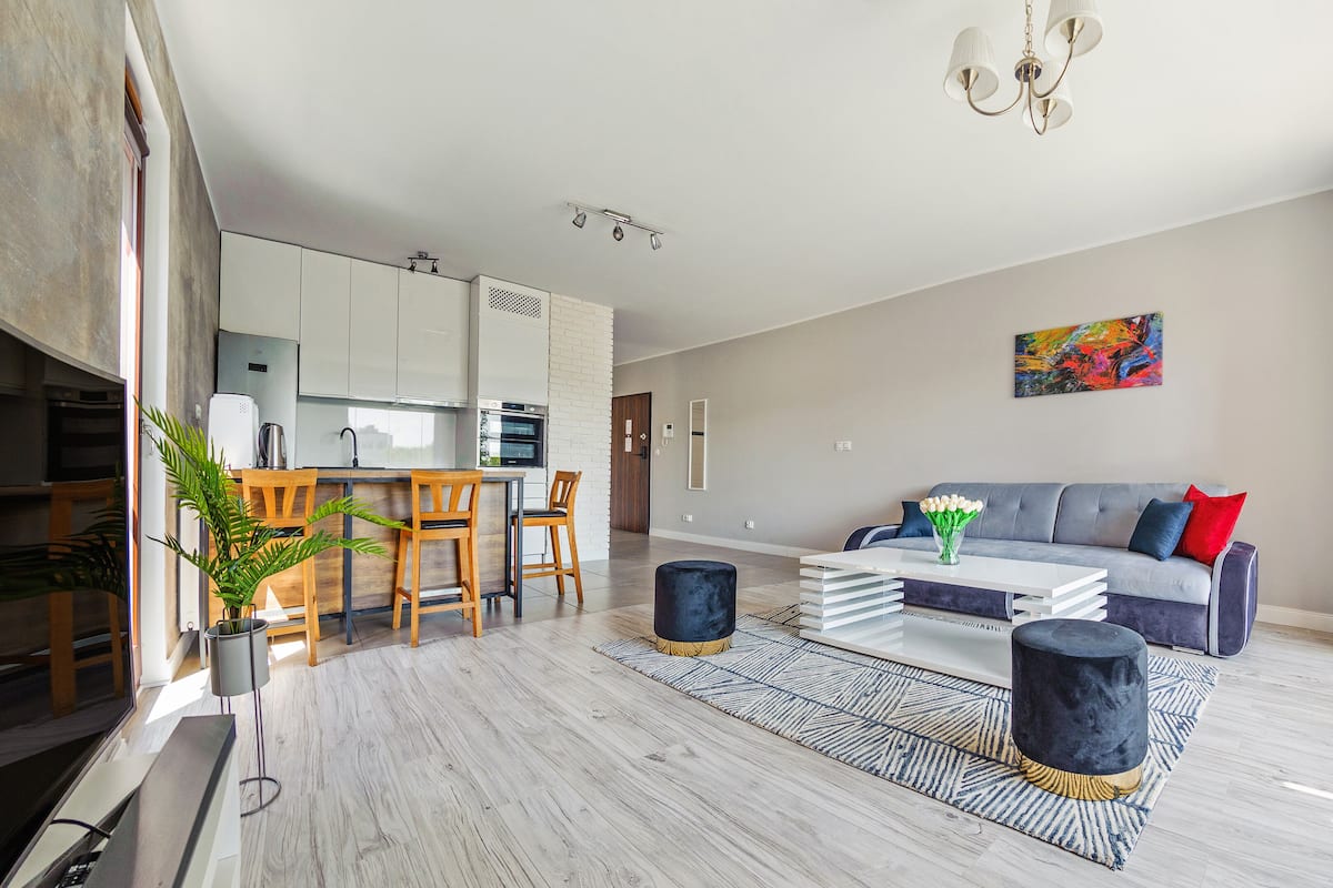 Un salon moderne avec un canapé gris, une table basse et un coin repas comprenant des chaises en bois et une petite table.