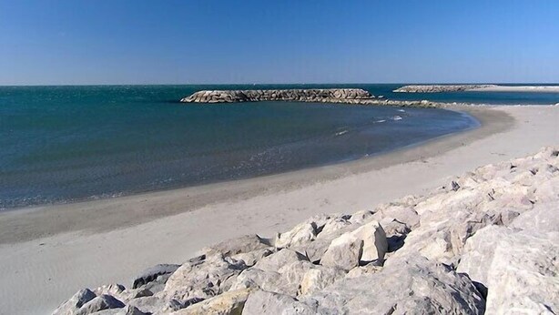 Una platja amb formacions rocoses i aigües tranquil·les.