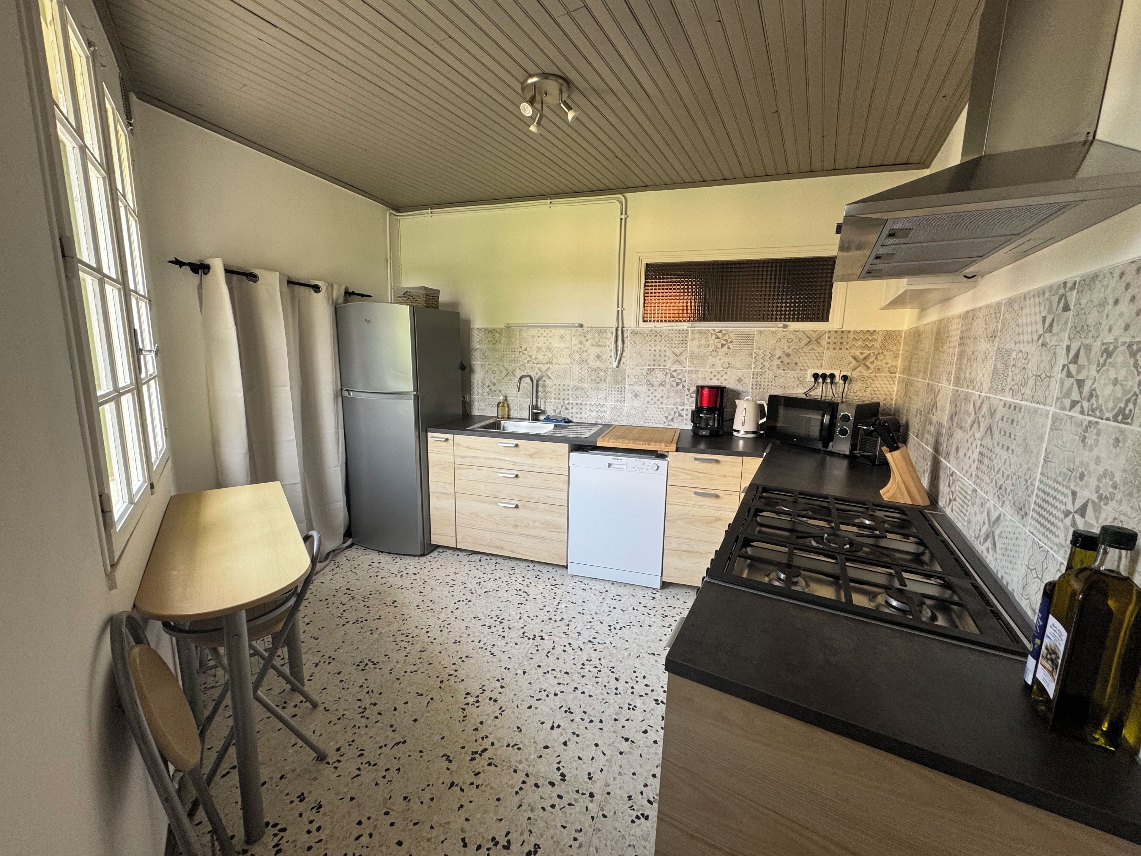 Cocina compacta con refrigerador, estufa, microondas y lavaplatos.