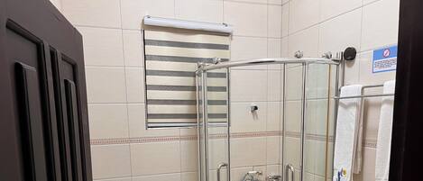 Een hoekbadkamer met een douchekabinet, toilet en handdoekrek met handdoeken.