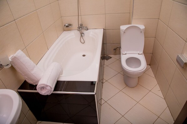 A bathroom with a bathtub, toilet, and a towel rack.