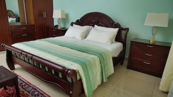 A neatly made bed with a wooden headboard, a bedside table with a lamp, and a nightstand with a lamp.