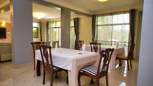 A dining area with a table set for six, surrounded by wooden chairs with cushioned seats.