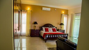 A hotel room with a bed, bedside tables, a TV, and a window with curtains.