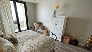 Una camera da letto con un letto, un armadietto bianco, una sedia e un tavolino con una pianta.