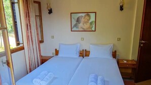 A double bed with white linens and rolled towels, a wooden headboard, a small bedside table, and a wall-mounted picture. - Eleni's Apartments & Studios (Corfu)